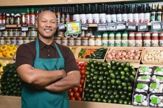 A grocery store worker standing in front of the goods.