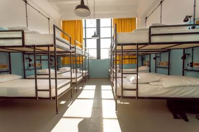 Six bunkbeds packed in a hostel room.