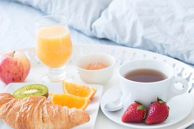 A breakfast meal on a tray on a bed.